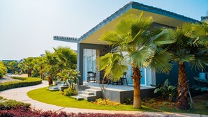A modern house with a flat roof, large windows, and a covered porch. - Basalt Paradise Resort And Spa (Halol)