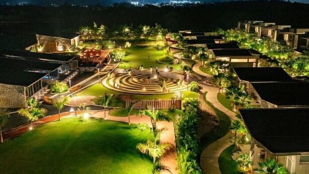 A resort with a central circular garden, multiple buildings, and well-lit pathways. - Basalt Paradise Resort And Spa (Halol)