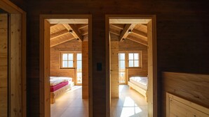 L’intérieur d’un chalet en bois comprend deux chambres, chacune étant équipée d’un lit et d’une fenêtre.