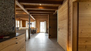 A spacious wooden interior with a kitchen area, a dining table, and a large window allowing natural light.
