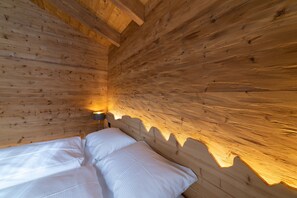 A wooden cabin interior with a bed and a nightstand.