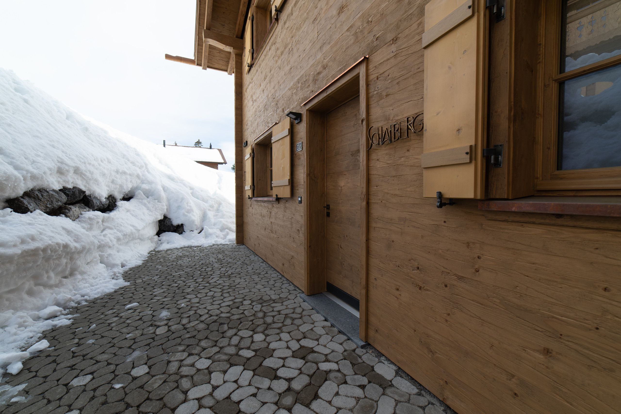 A wooden building with a door labeled 'Schw. G.' and a window with a view of the sky.