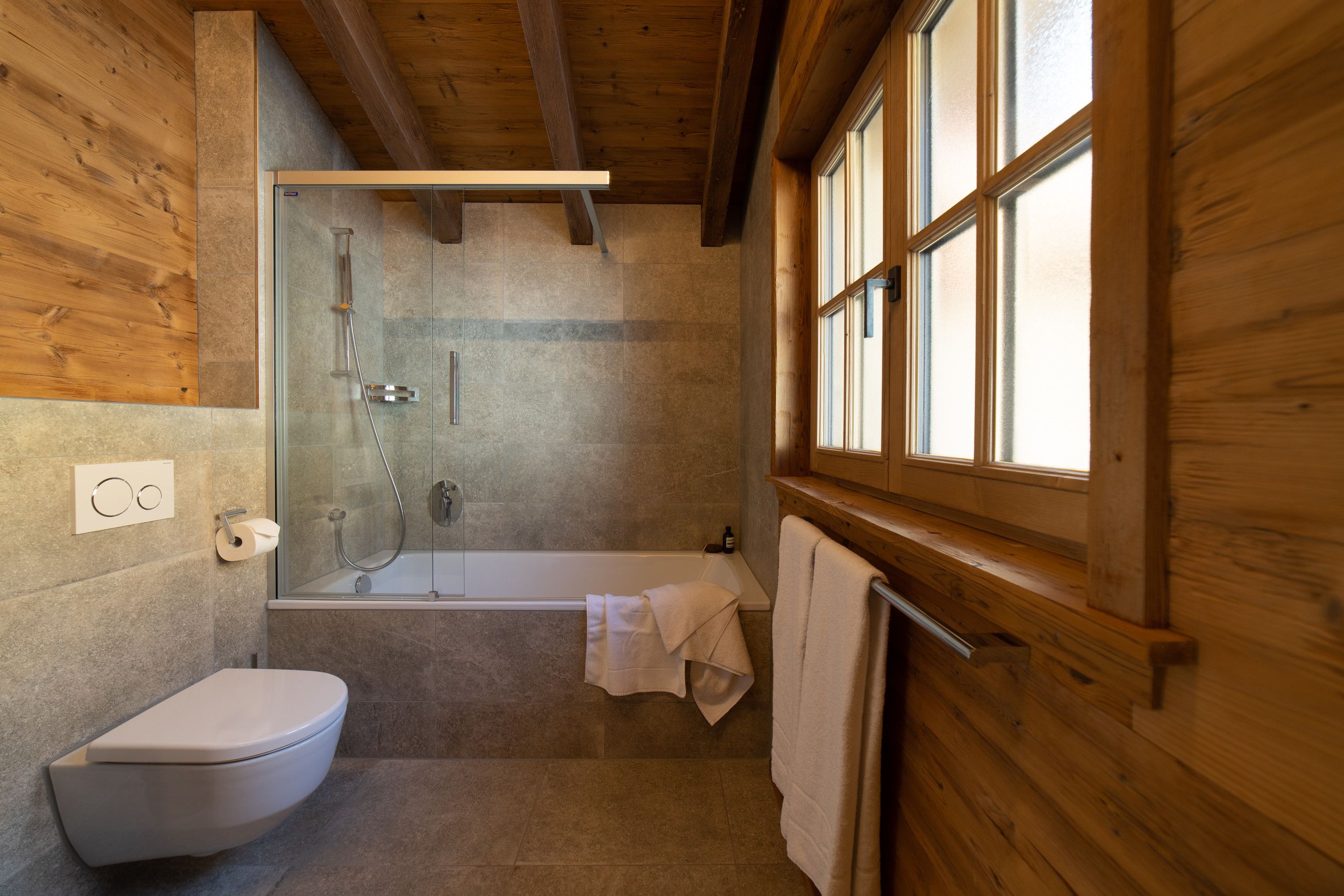 A bathroom with a toilet, a glass-enclosed shower, and a bathtub.