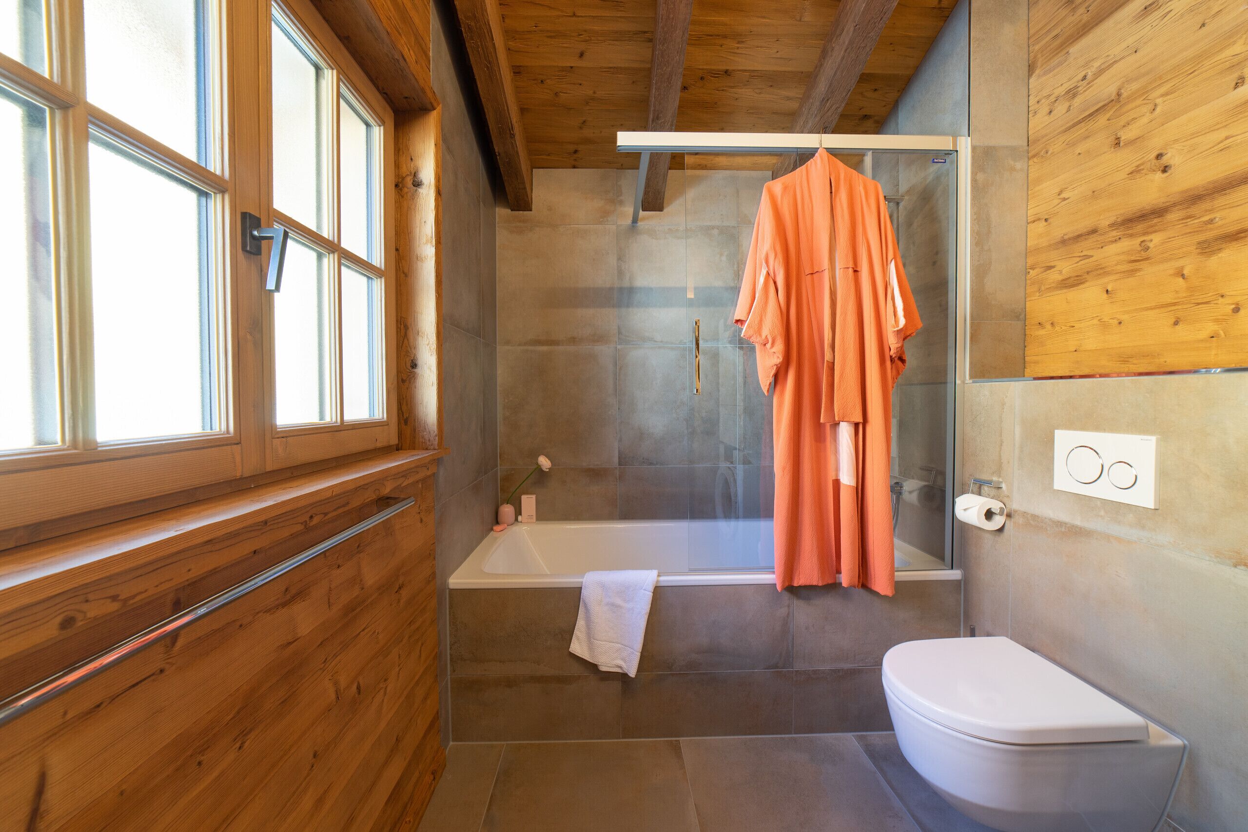 A bathroom with a bathtub, a toilet, and a shower area.