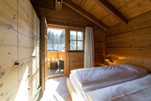A wooden cabin with a bed, a table, and a window with curtains.