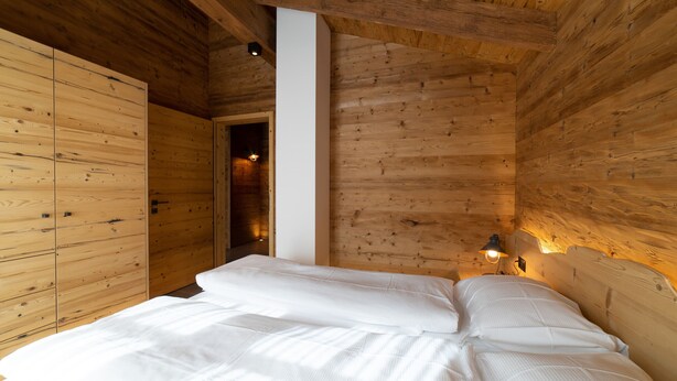 A wooden room with a bed, a wardrobe, and a nightstand with a lamp. - Schibenstoll 4-room chalet near the mountain railways (Wildhaus)