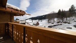 Un balcón de madera con vistas a un paisaje nevado con casas y un cielo despejado.