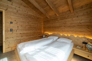 Una habitación de cabaña de madera con una cama, una mesita de noche y un aplique de pared.
