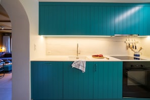 Et moderne køkken med turkis skabe, en marmor bordplade og en stålvask.
