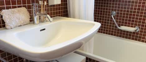 Un baño con lavamanos blanco, espejo, toalla y bañera.