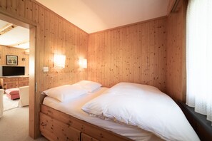 Una habitación con paneles de madera, una cama, un televisor y una pequeña zona de estar.