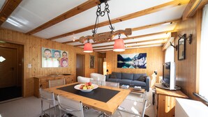 Interior de madeira com uma mesa de jantar, cadeiras, um sofá e uma televisão.