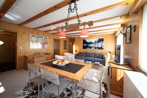 Un interior de madera con una mesa de comedor, sillas, un sofá y un televisor.
