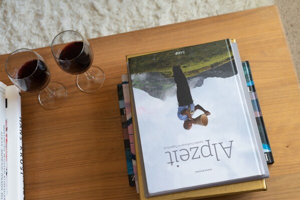 Un libro titulado 'Alpgeist' sobre una mesa de madera con dos copas de vino tinto.