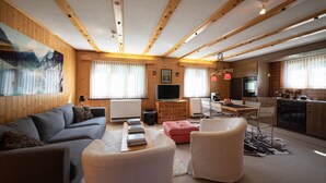 Uma sala de estar moderna com sofá, banquinho e televisão.