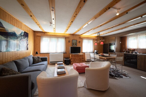 Una sala de estar moderna con un sofá, un reposapiés y una televisión.