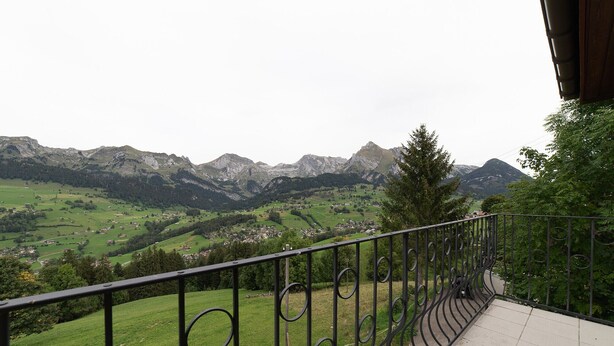 Un balcón con barandilla de metal que ofrece vistas a un paisaje montañoso.