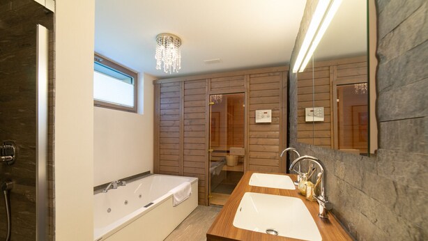 Une salle de bain moderne avec une baignoire, deux lavabos, un meuble-lavabo et un lambris en bois.