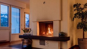 A modern living room with a fireplace, wooden flooring, and a large window.