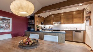A modern kitchen with wooden cabinets, a central island, and a dining area with a table and chairs.