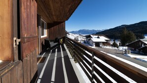 Un balcón de madera con vistas a un paisaje montañoso nevado.