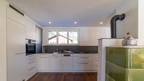 Una cocina moderna con armarios blancos, una estufa negra y un ventanal con vista a un edificio.