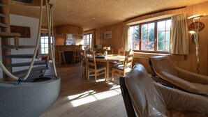 Interior de madera con comedor, sillón de masaje y escalera con cuerda.