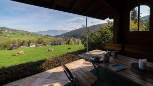 Un espacio de estar al aire libre cubierto con vistas a un campo verde y casas a lo lejos.