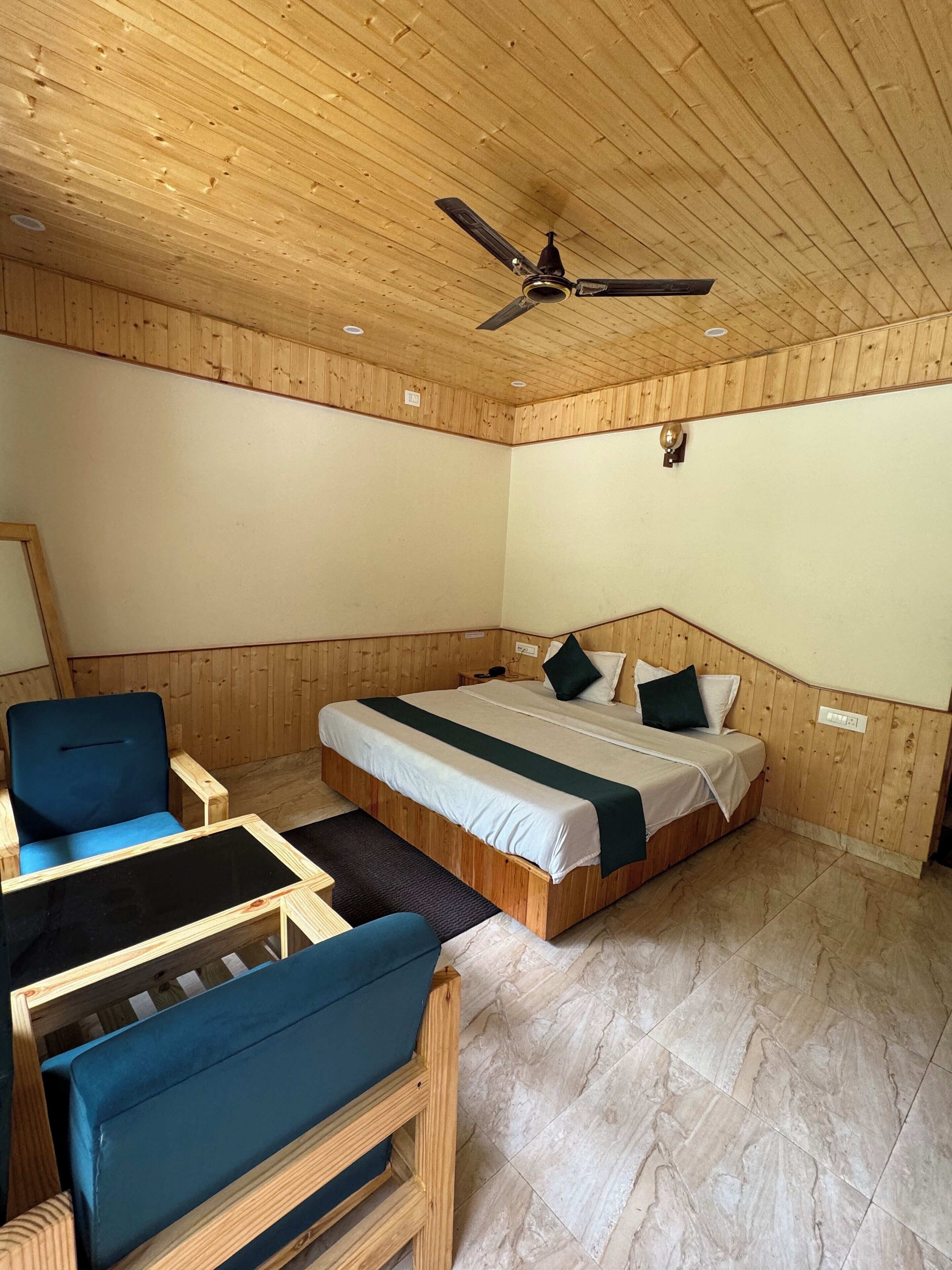 Una stanza con rivestimento in legno, un letto, una sedia e una ventola a soffitto.
