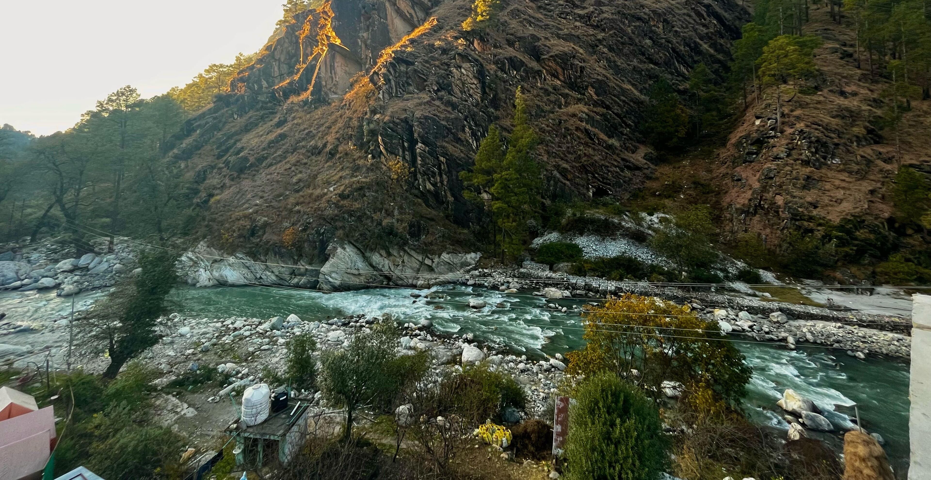 Ein Fluss fließt durch eine gebirgige Landschaft mit felsigem Gelände und vereinzelter Vegetation.
