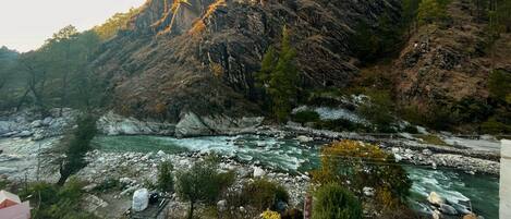 A river flowing through a mountainous area with rocky terrain and sparse vegetation.