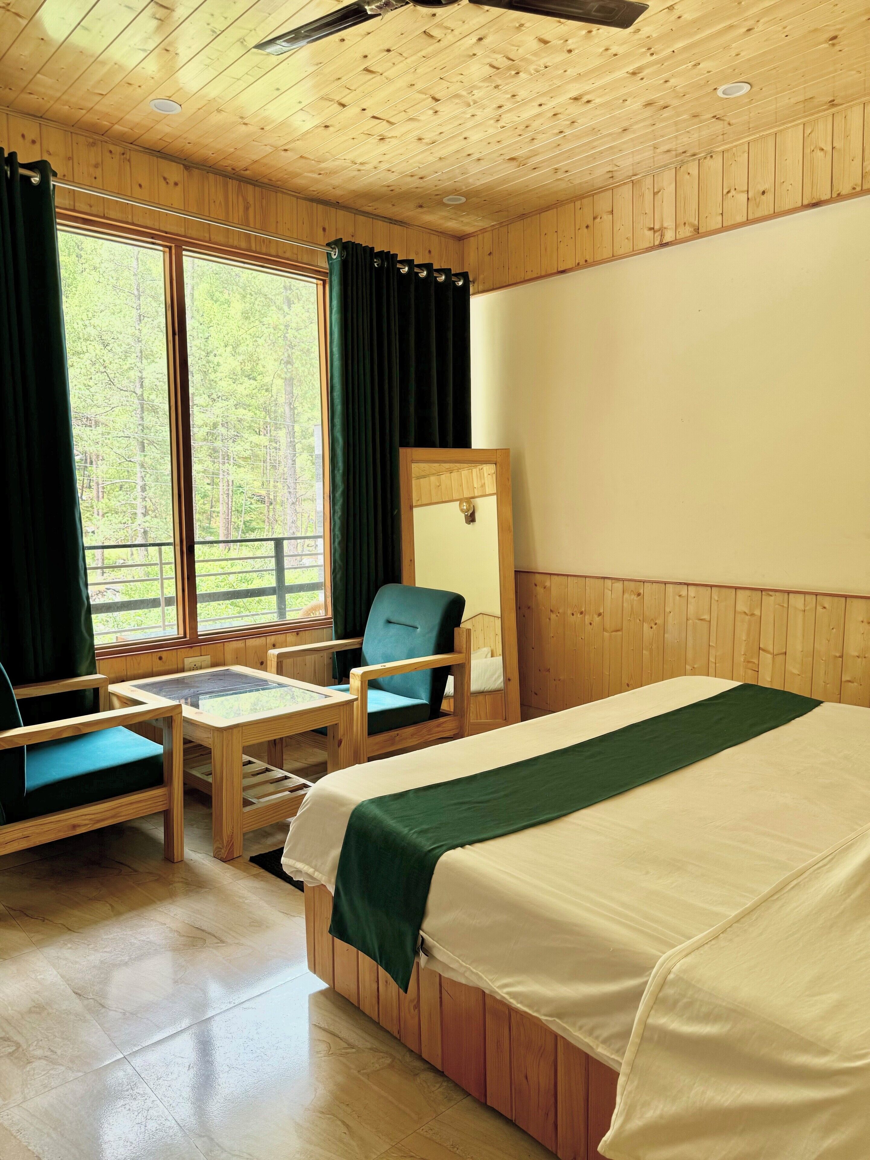 Ein Zimmer mit einem Bett, zwei Stühlen, einem Tisch und einem Spiegel.
