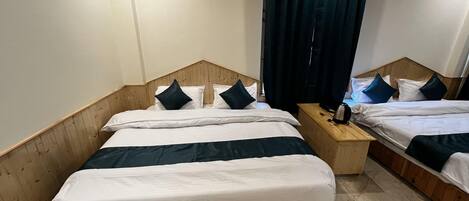 A hotel room with two beds, wooden headboards, a nightstand, and a curtain.