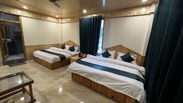 Habitación de hotel con dos camas, cabeceros de madera, un ventilador de techo y una mesa de vidrio.