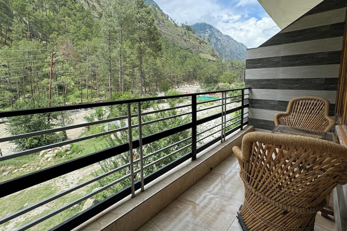Un balcón con vistas a un paisaje montañoso, una silla de mimbre y un muro a rayas.