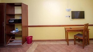 Ein Zimmer mit einem Holztisch, einem an der Wand befestigten Fernseher und einem Schrank aus Holz.