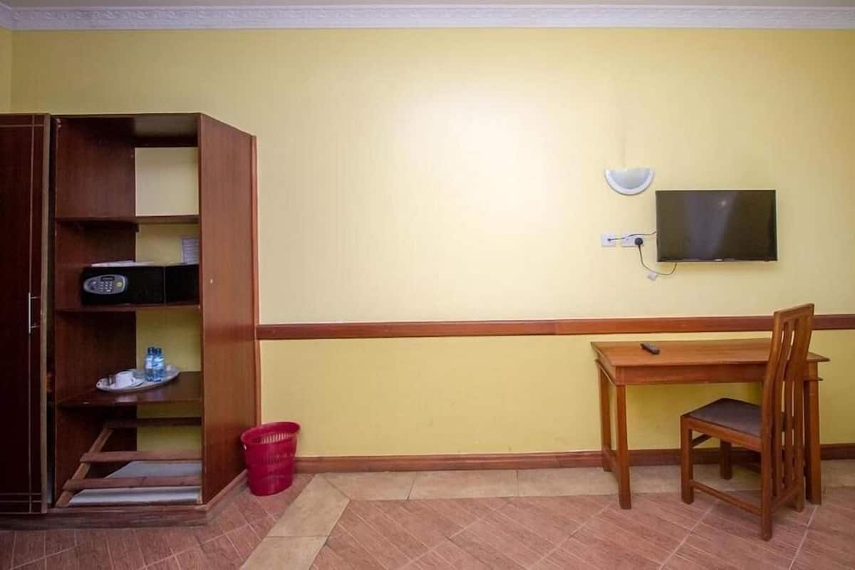 Una habitación con un escritorio de madera, un televisor instalado en la pared y un armario de madera.