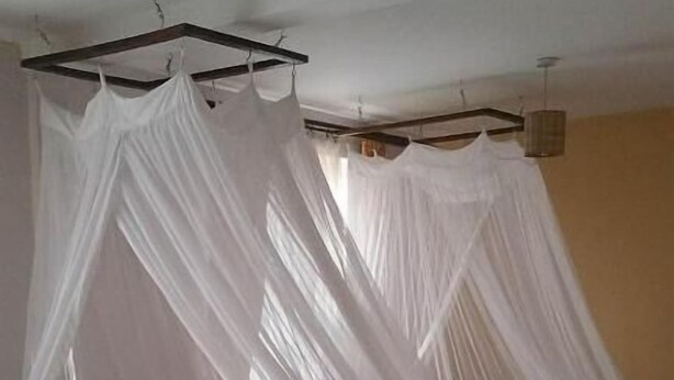 Ein Bett mit Baldachin, einem hölzernen Kopfteil und einer braunen Tagesdecke.