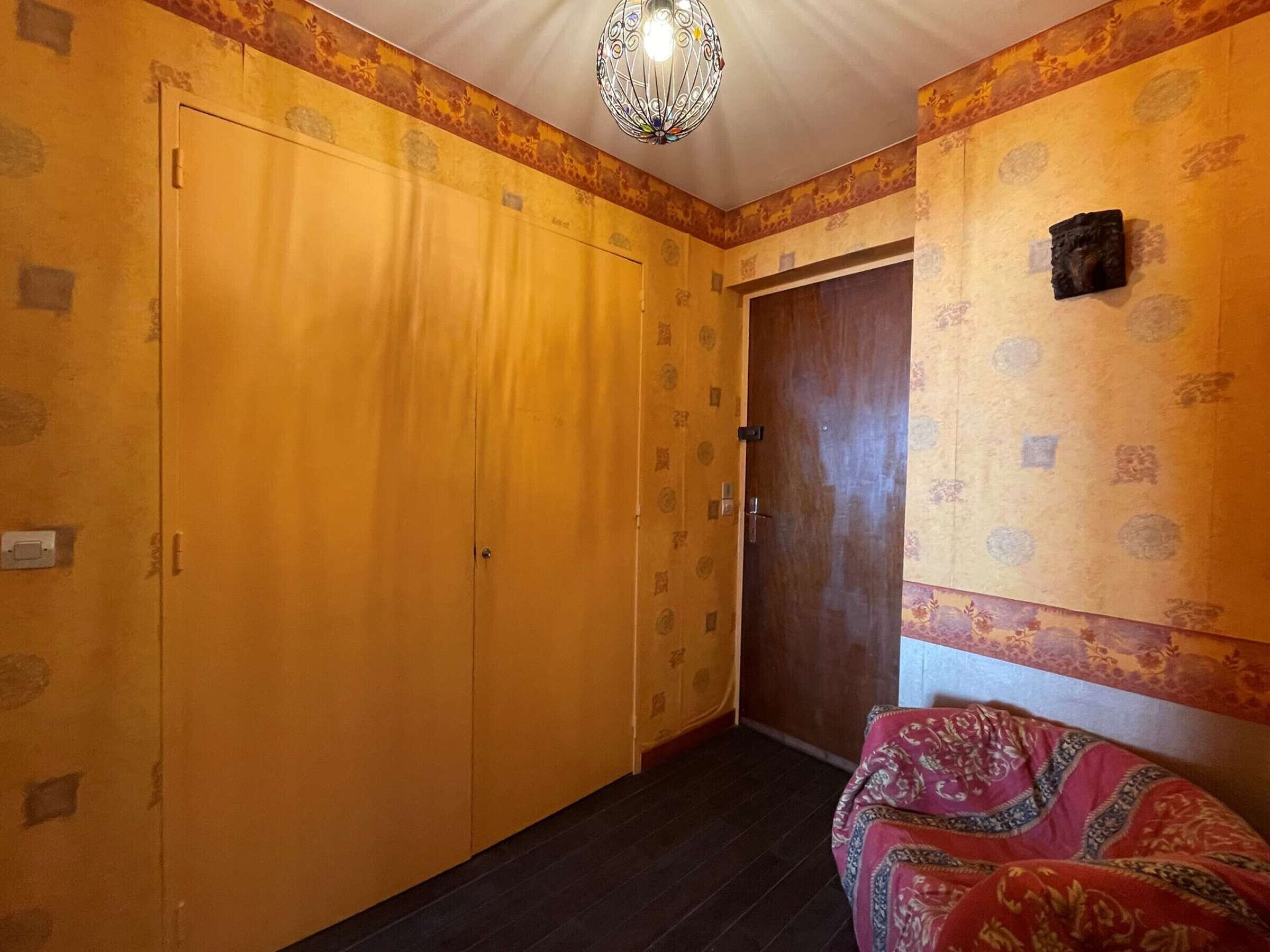 Een kamer met een grote kledingkast, een behang met patroon en een decoratieve lamp.