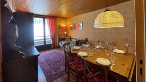 A dining area with a wooden table set for four, surrounded by chairs.