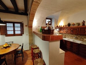 Une cuisine avec une table et des chaises en bois, une fenêtre et un mur recouvert de carreaux.