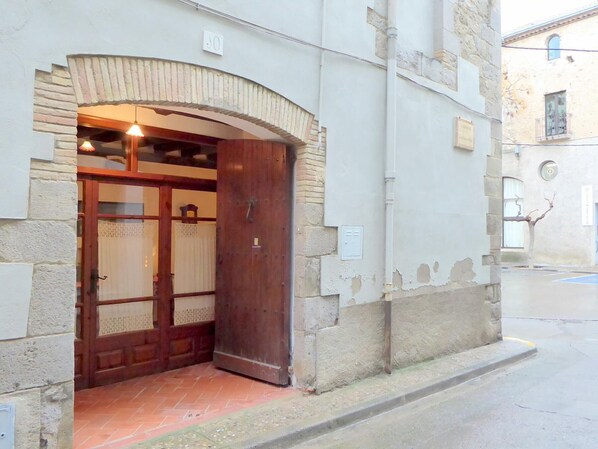 Une entrée d’immeuble avec une porte en bois et un arc en pierre.