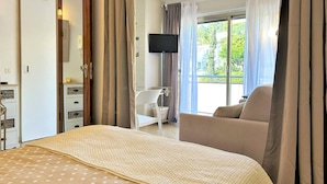 A hotel room with a bed, a TV, a balcony with a chair, and a desk with a chair.