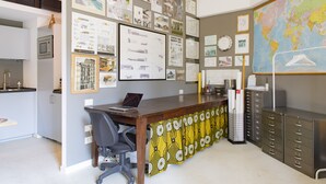 Un bureau moderne, équipé d’un bureau, d’une chaise et d’un grand mur où sont affichés des plans d’architecture et une carte du monde.