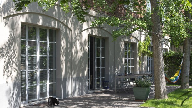 Un bâtiment doté de grandes fenêtres et d’un trottoir dallé.