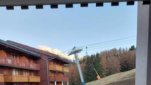 Un hotel con balcón con vistas a una pista de esquí y un telesilla.