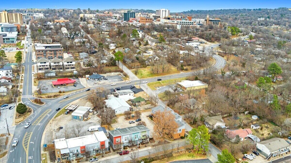 Vista aérea de un pueblo con edificios residenciales y comerciales, calles y una estructura destacada con techo rojo.