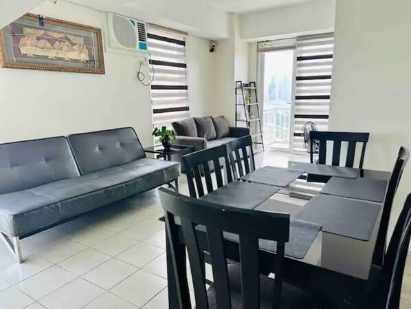 A modern living room with a sofa, dining table, chairs, and a small side table.