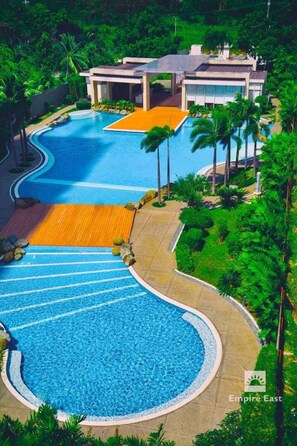 A resort with a large, curved swimming pool, a modern building, and lush greenery.