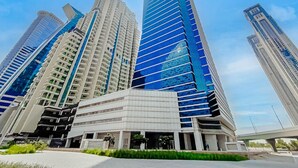 Un immeuble moderne de grande hauteur, doté de nombreux étages, de grandes fenêtres et d’un hall d’entrée imposant.
